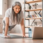 Sporty,Middle-aged,Caucasian,Woman,Standing,In,Plank,Position,Using,Laptop